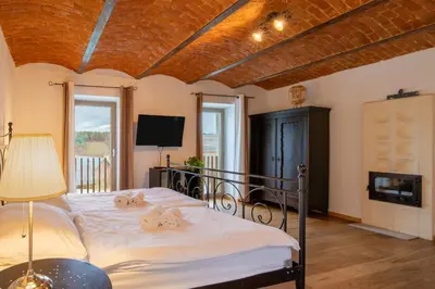 a bedroom with a bed with white sheets and a television at Goricko Natural Chalets in Križevci