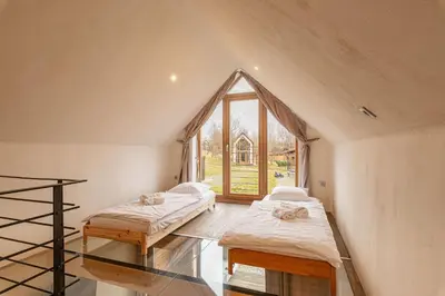 two beds in a room with a large window at Goricko Natural Chalets in Križevci
