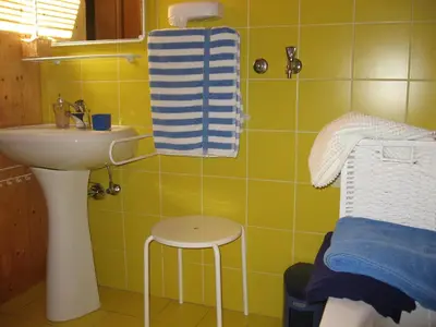 a yellow bathroom with a sink and a stool at Apartments Bledea in Bled