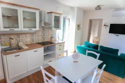 a kitchen and living room with a white table and chairs at APART HOTEL ASTERIA in Ljubljana