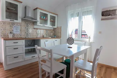 a kitchen with white cabinets and a table and chairs at APART HOTEL ASTERIA in Ljubljana