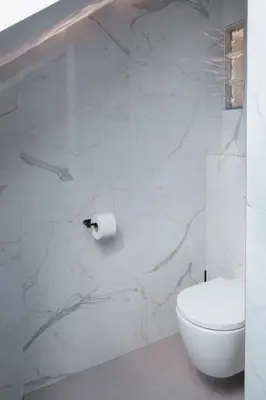 a white bathroom with a toilet and a roll of toilet paper at HIŠA PUTR in Trzin