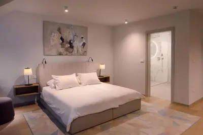 a bedroom with a large white bed with two lamps at HIŠA PUTR in Trzin