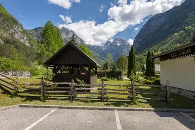 a building with a fence and mountains in the background at Metoja in Soča