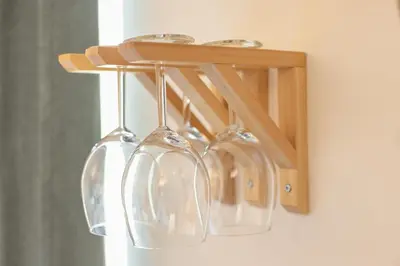 four wine glasses hanging from a wooden rack at VILA KLARA apartments in Ljubljana