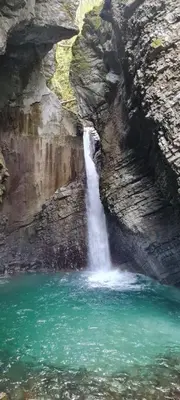 a waterfall in a canyon with a body of water at Apartma Soča Oasis in Srpenica