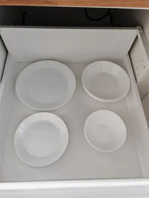 a drawer with four white plates in it at YELLOW APARTMENT WITH FREE PARKING in Ljubljana