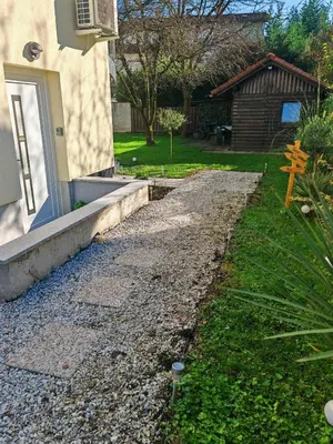 a gravel driveway next to a house with a church at YELLOW APARTMENT WITH FREE PARKING in Ljubljana