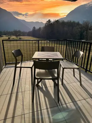 a table and chairs on a balcony with a view of mountains at Soca Valley Suites in Bovec