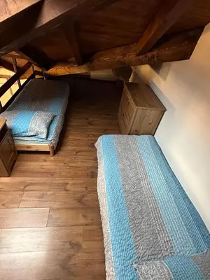 two beds in a room with wooden floors at Apartma Popeye in Bovec