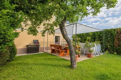 a patio with a wooden table and a white canopy at House Dijana With Pool - Happy Rentals in Nova Vas