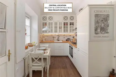 a kitchen with white cabinets and a table and chairs at Historical Caserne Apartment in Ljubljana