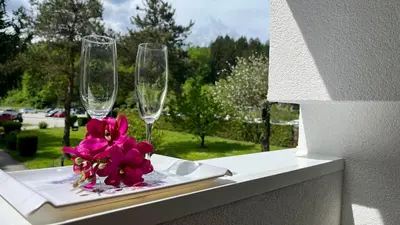 a table with two wine glasses and a pink flower on it at Apartma Jurka in Podčetrtek