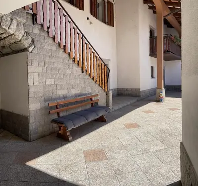 a wooden bench sitting next to a building with stairs at Homestead - Domačija - Nabergoj in Podnanos