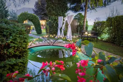 a garden with a pond with a bridge and flowers at Apartments Ladka in Begunje na Gorenjskem