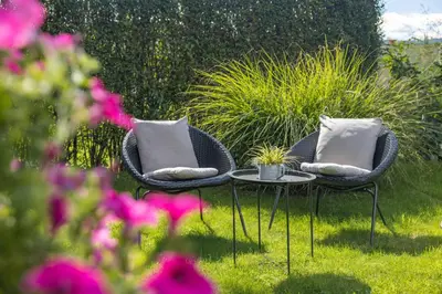 two chairs with pillows and a table in a garden at Apartments Ladka in Begunje na Gorenjskem