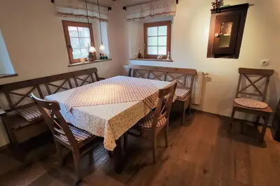a dining room with a table and chairs and windows at MaLu vintage house with garden in Logatec
