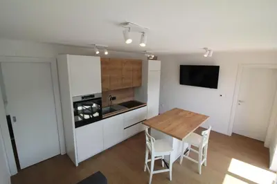 a kitchen with a wooden table and white cabinets at Naia Apartments in Novo Mesto