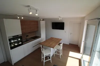 a kitchen with a wooden table and white cabinets at Naia Apartments in Novo Mesto
