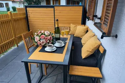 a table with a bottle of wine and flowers on a patio at APARTMA MORAVSKE TOPLICE in Moravske Toplice