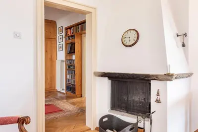 a fireplace in a living room with a clock on the wall at Spacious And Historic Villa With Bled Castle View in Bled