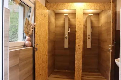 a bathroom with a shower with wooden walls at T'glamp Bee house in Rovte