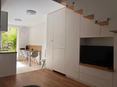 a kitchen with white cabinets and a television in a room at LiLan apartment in Maribor