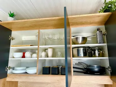 a cabinet filled with dishes and utensils at BREZA mobile house BIG BERRY in Metlika