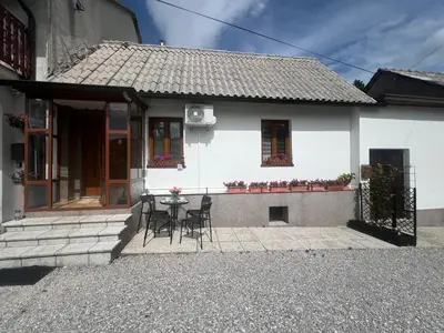a white house with a table and chairs in front of it at Apartma Lozar in Ajdovščina