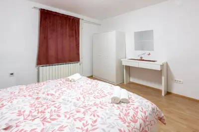 a white bedroom with a bed and a desk at Apartma Lozar in Ajdovščina