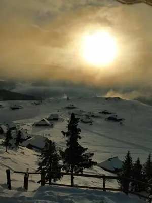 a snow covered mountain with the sun in the sky at Črnuški dom na Mali planini in Krivčevo
