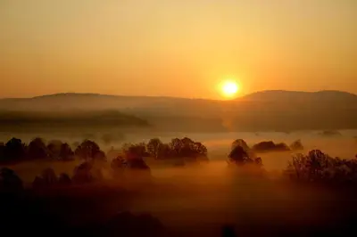 a misty sunrise with the sun in the background at Apartment Šefic in Planina