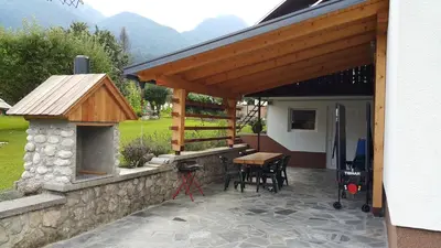 a patio with a table and an outdoor oven at Apartments Klemenčič in Bohinj
