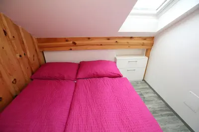 a bedroom with a bed with pink sheets at Apartments Klemenčič in Bohinj