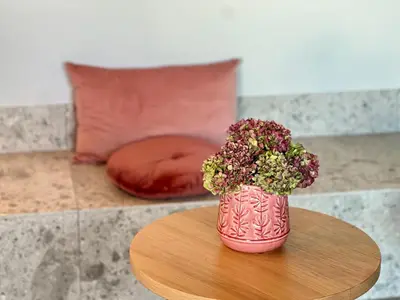 a pink vase with flowers sitting on a table at Stara lipa Tašner kitchen & P & garage - self check-in in Maribor