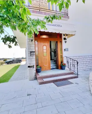 a front entrance to a house with a brown door at Stara lipa Tašner kitchen & P & garage - self check-in in Maribor