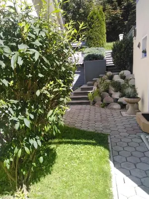 a garden with a stone walkway with plants and stairs at Apartments Irena in Kranjska Gora