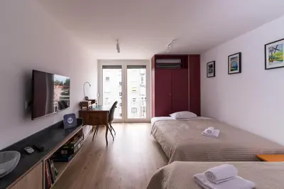 two beds in a room with a television and a desk at Jojo apartment in Ljubljana