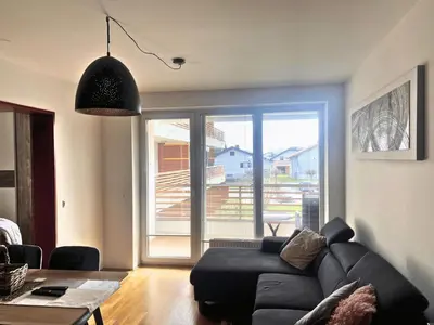 a living room with a black couch and a large window at Apartment Hakuna Matata in Moravske Toplice