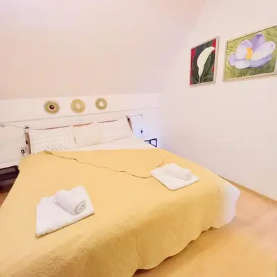 a bedroom with a yellow bed with two white towels on it at Miabella House - 2 bedrooms and terrace in Brežice