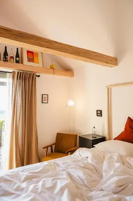 a bedroom with a bed and a chair and a window at MÓD in Lendava