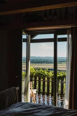 a bedroom with a bed and a balcony with a view at MÓD in Lendava