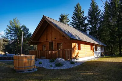 a log cabin with a barrel in front of it at Alpine Retreat Apartments Šurc in Rateče