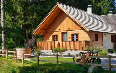 a wooden house with a bike in front of it at Alpine Retreat Apartments Šurc in Rateče