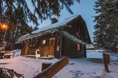 a log cabin in the snow with christmas decorations at Apartment Zarja - Trije Kralji in Zgornja Ložnica