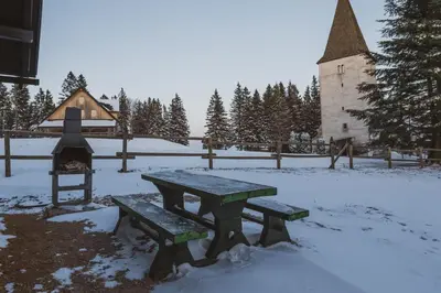 a picnic table in the snow next to a church at Apartment Zarja - Trije Kralji in Zgornja Ložnica