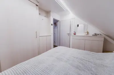 a white bedroom with a bed and a staircase at Apartment Zarja - Trije Kralji in Zgornja Ložnica