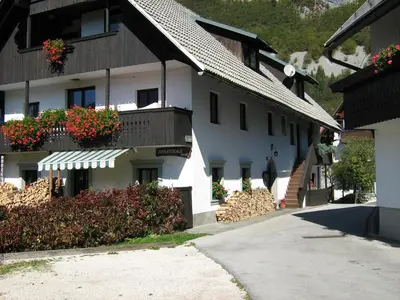 a white building with flower boxes on the balconies at Apartmaji Hodnik Stara Fužina in Bohinj