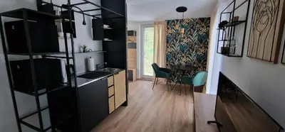 a kitchen with black cabinets and a dining room at Studio Apartment Aurora in Škofljica