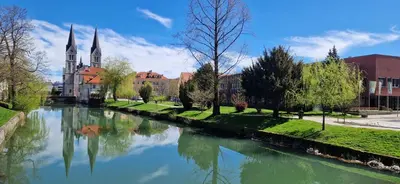a river in front of a church with a cathedral at Deteljica in Kočevje